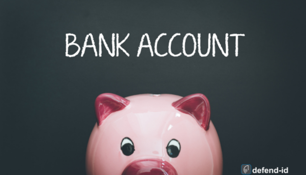 Pink piggy bank on a dark background with 'BANK ACCOUNT' written in white chalk above, featuring a watermark for 'defend-id'